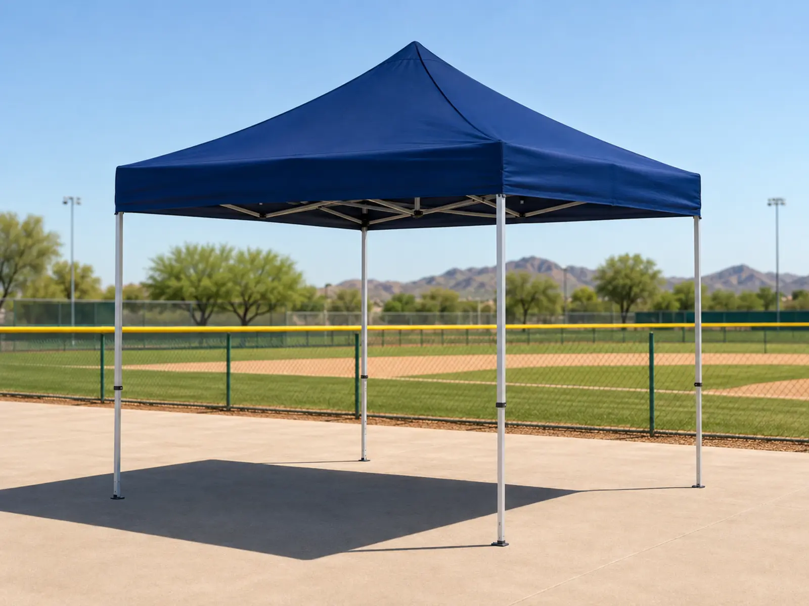 Portable shade canopy set behind dugout-side seating at a Phoenix youth baseball venue.
